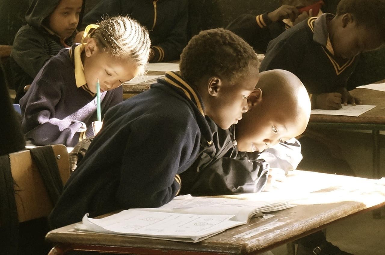 Students seated together at a desk, working through their books